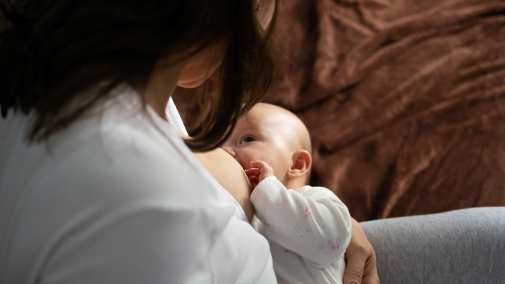 A baby breastfeeding from their mom, from a top down view. To show that breastfeeding is important to avoid SIDS